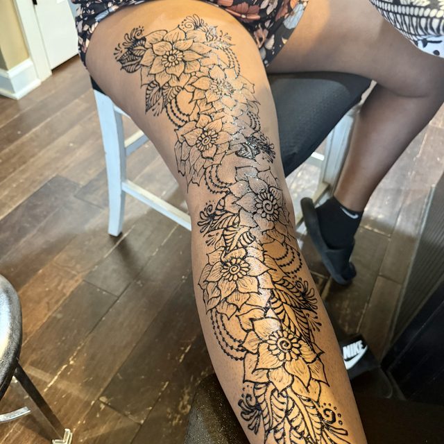 Floral and vine henna design on the leg