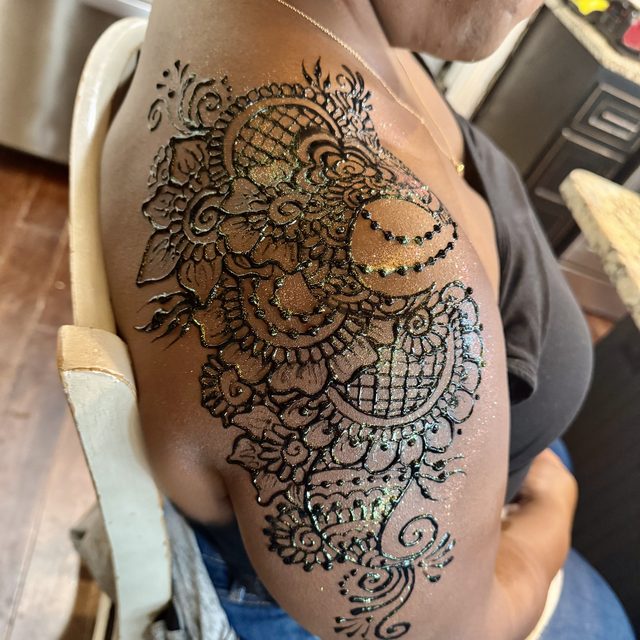 Glitter henna design covering the shoulder and upper arm