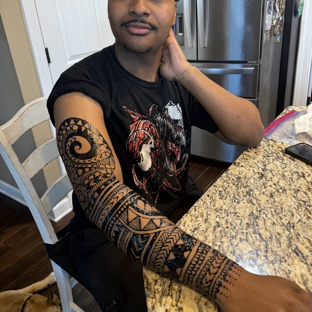 Tribal geometric henna sleeve design on the forearm